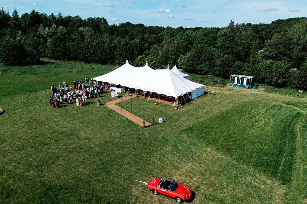Aerial view of a traditional marquee pitched on a lawn surrounded by woodland