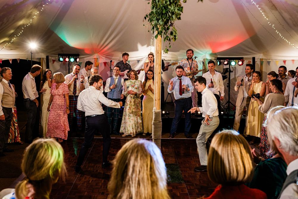 Guests dancing under coloured lights on a dance floor inside a marquee